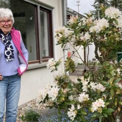Oma steht im Garten vor ihrem Haus